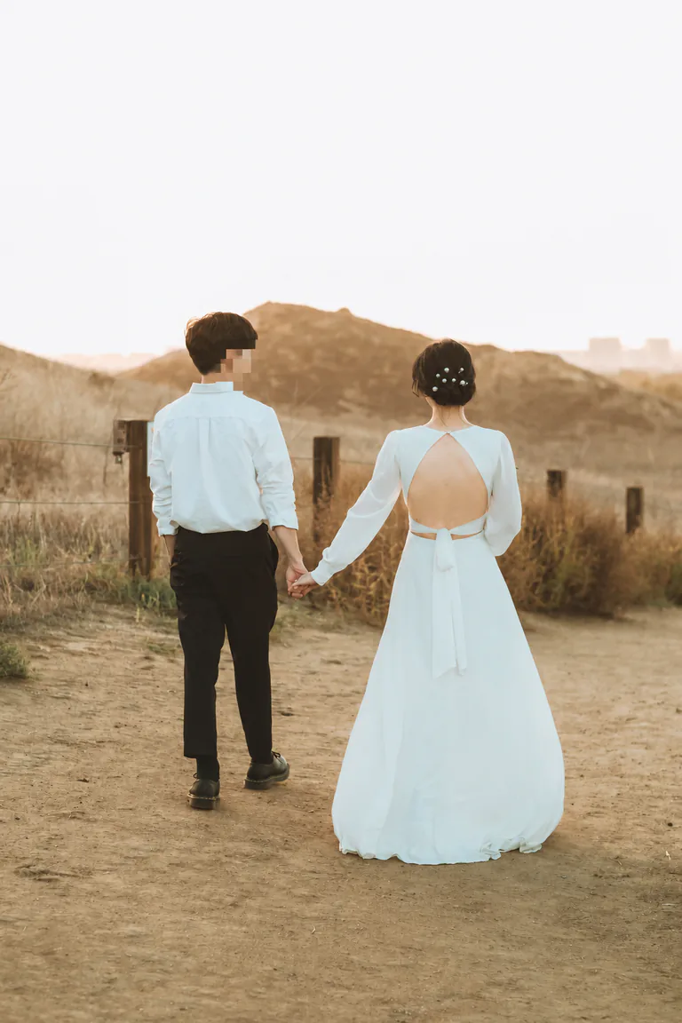 웨딩 복장의 두 사람이 손을 잡고 걷는 뒷모습