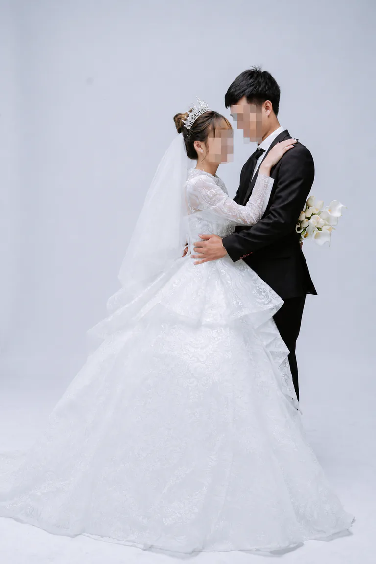 결혼식 복장의 두 사람이 흰 배경 앞에 서 있는 모습